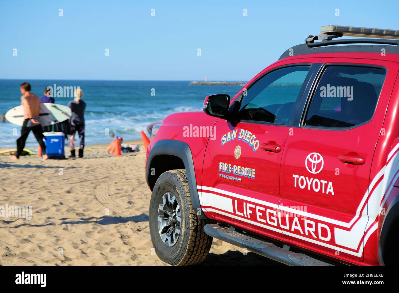 A red Toyota San Diego, California lifeguard fire and rescue truck on Ocean Beach with beachgoers in the background; sunny day in Southern California. Stock Photo