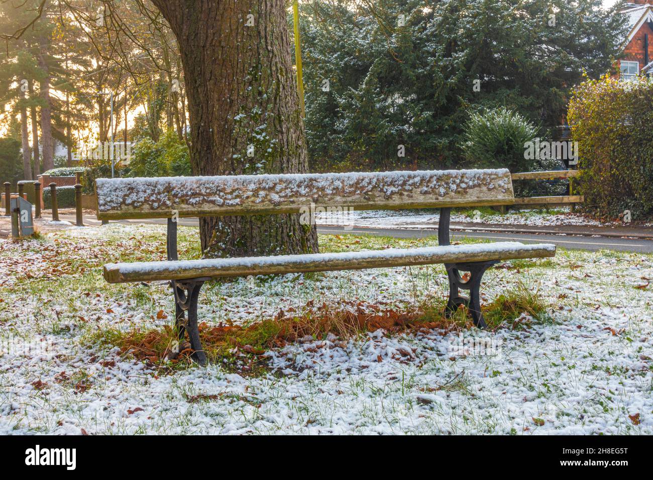 A snow covered bench on a winter's morning following a light covering of snow in Tilehurst, Reading, UK Stock Photo