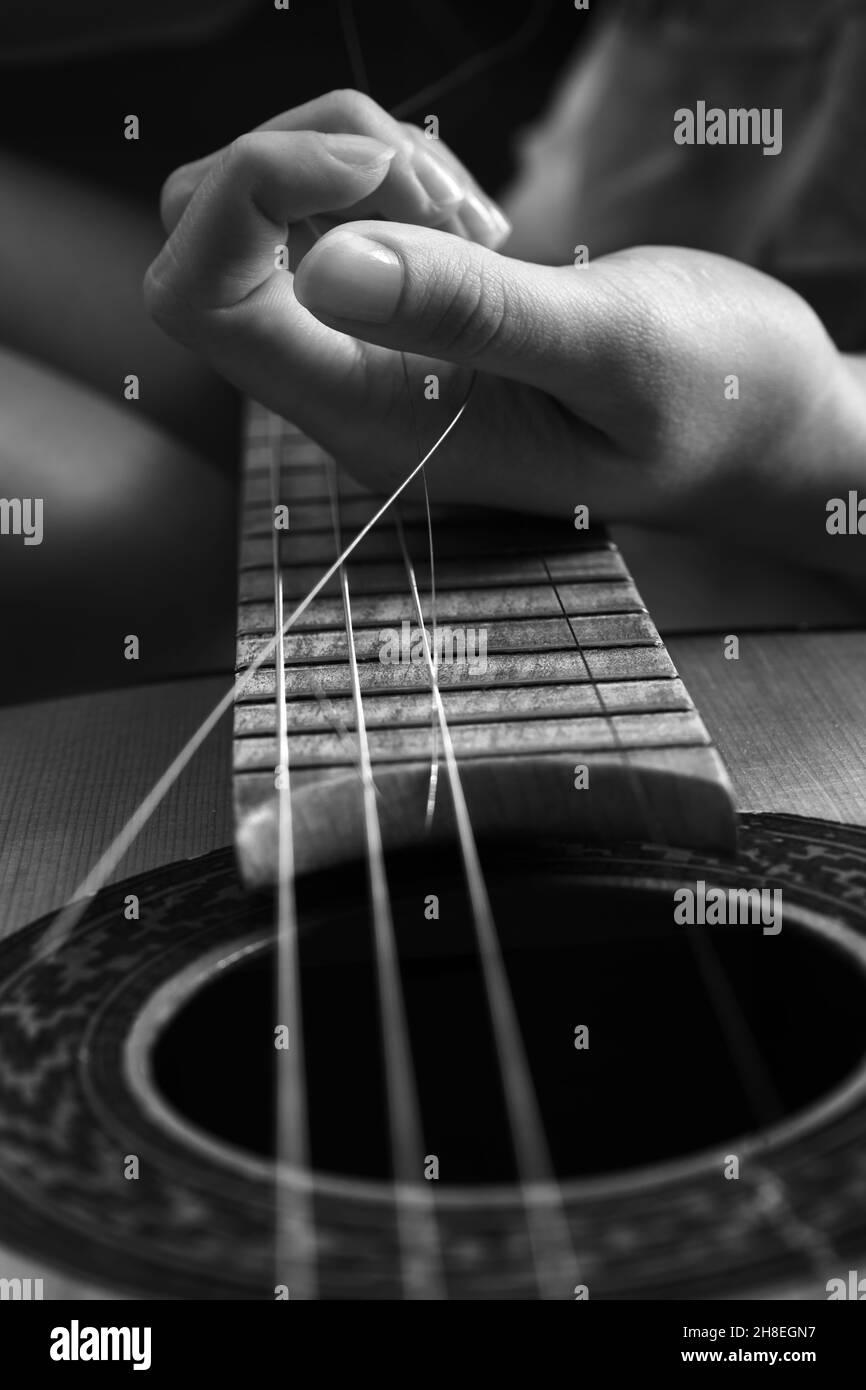 Broken guitar strings with female hands, guitar repair. monochrome image Stock Photo