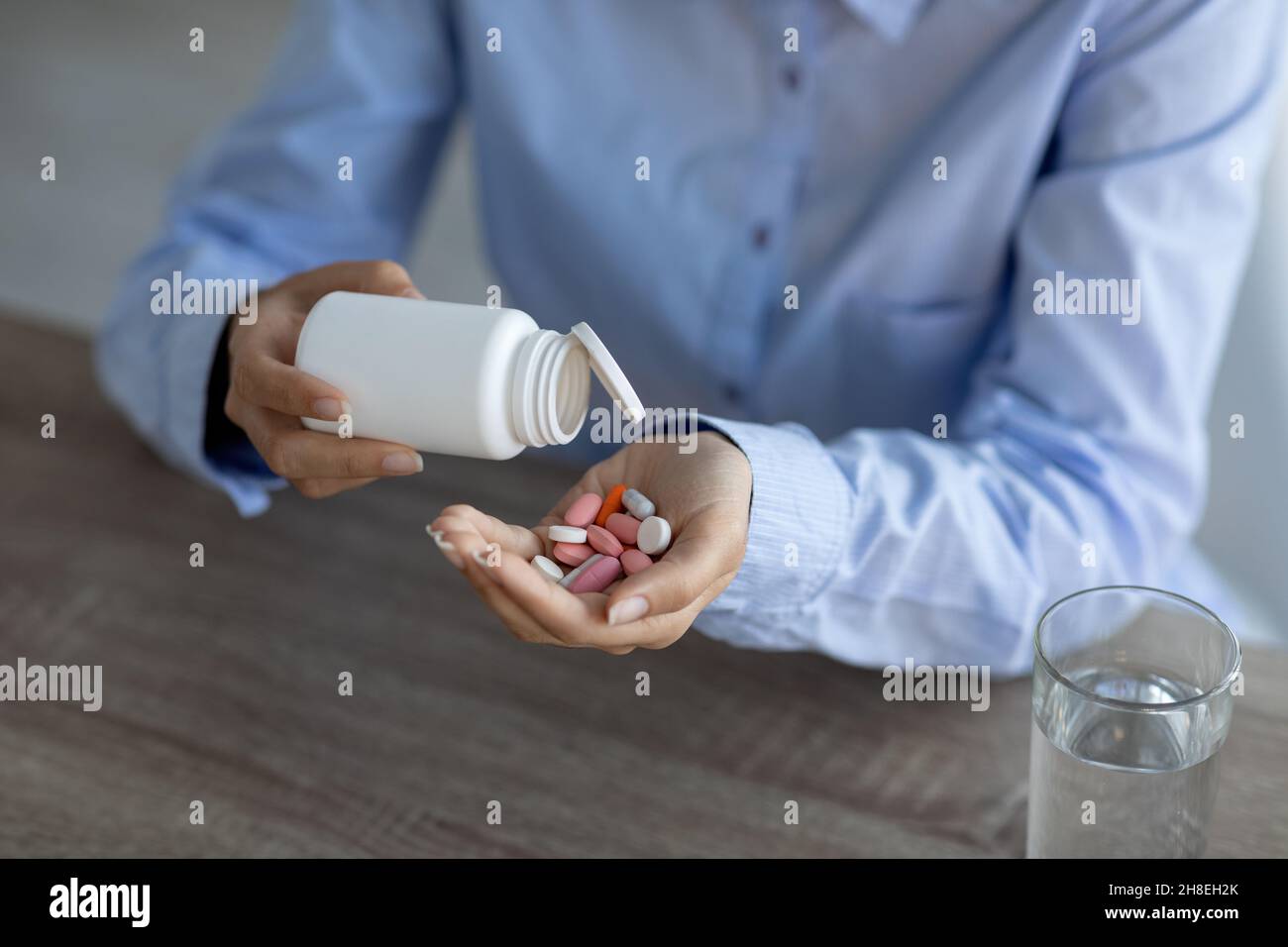 Cropped young indian woman worker pours pills on hand at workplace in office or home Stock Photo