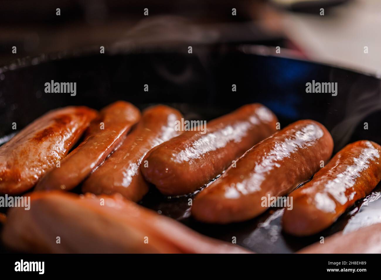 halfcut sausages are fried in oil in a black cast iron skillet Stock Photo Alamy