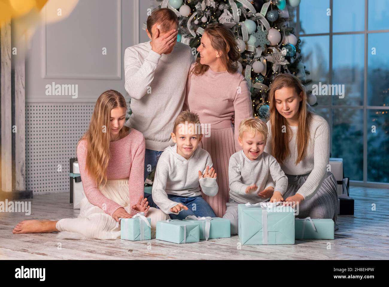 Big Happy family with many kids having fun and opening presents under the Christmas tree. Christmas family eve, christmas mood concept Stock Photo