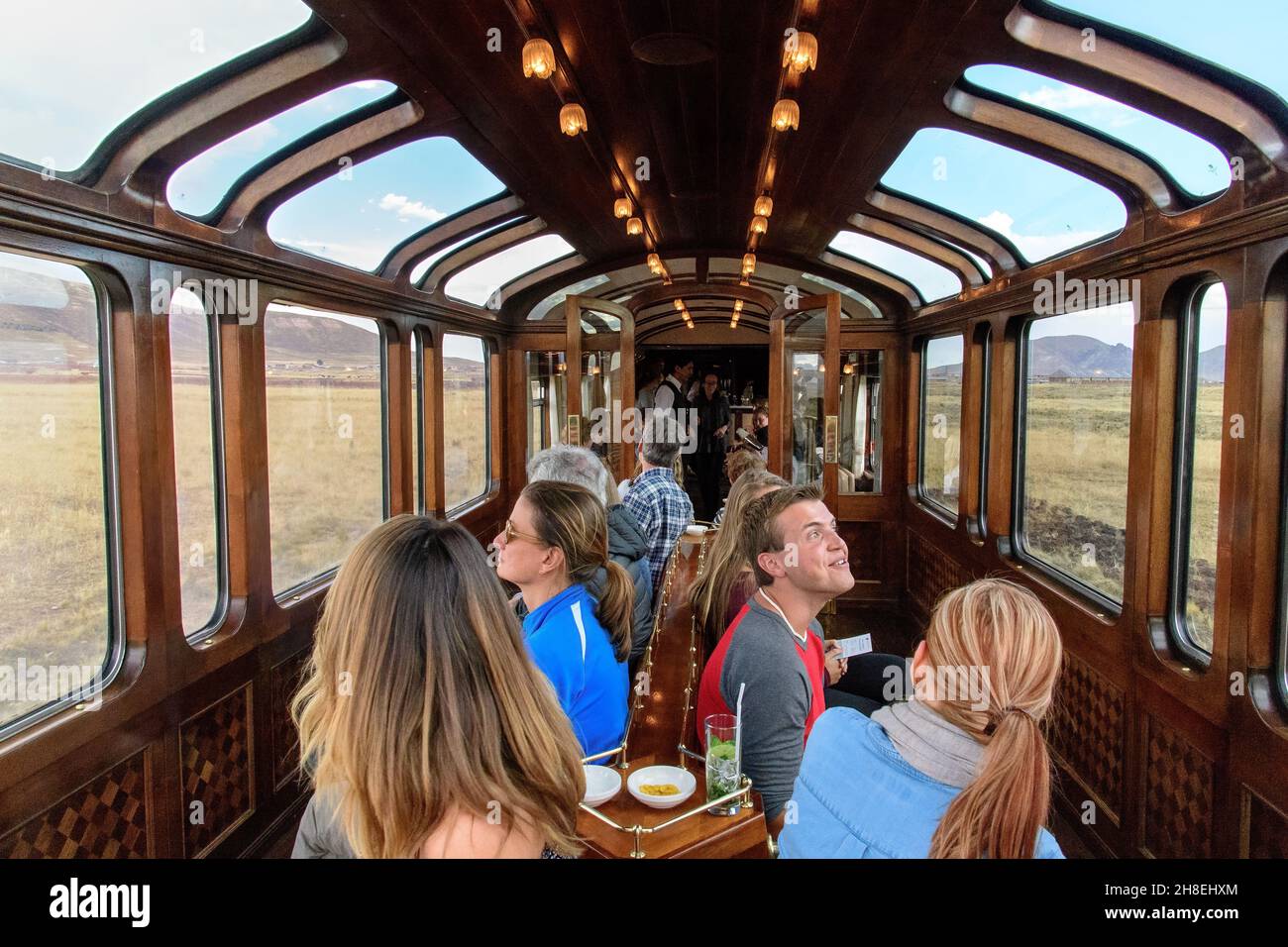 Passengers admire the scenery from the observation car on the Andean Explorer train,running between Cusco and Puno in Peru Stock Photo