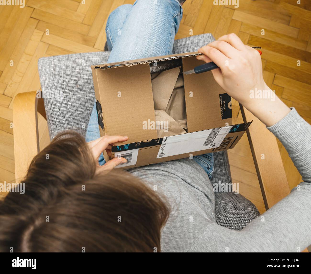 Overhead view of curious woman unboxing in the living room new Amazon Prime Parcel Stock Photo