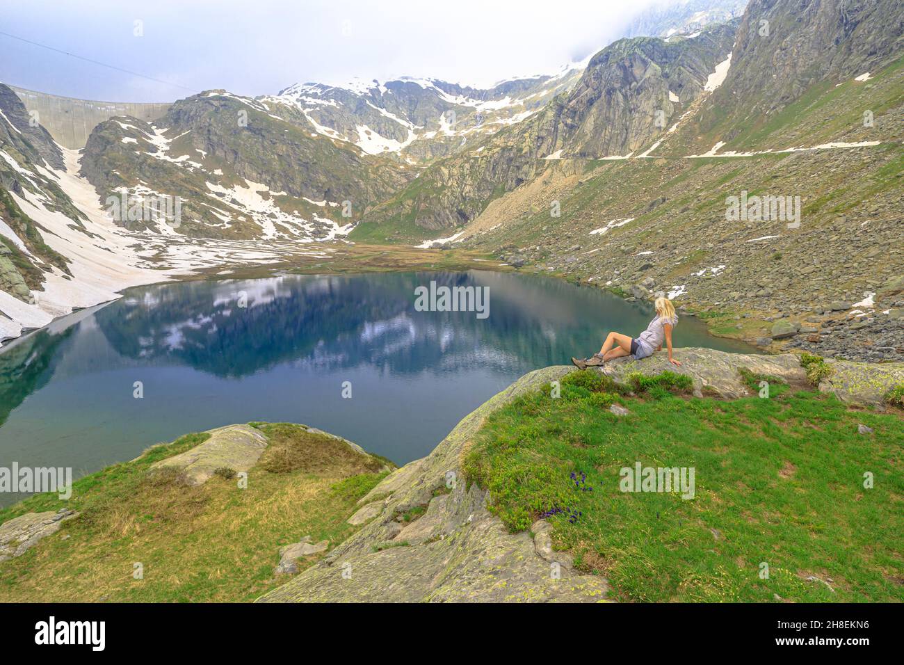Swiss reservoir in Maggia Valley of Ticino canton of Switzerland with Cavagnoo dan. Tourist woman resting during the trekking around the Lago Bianco Stock Photo