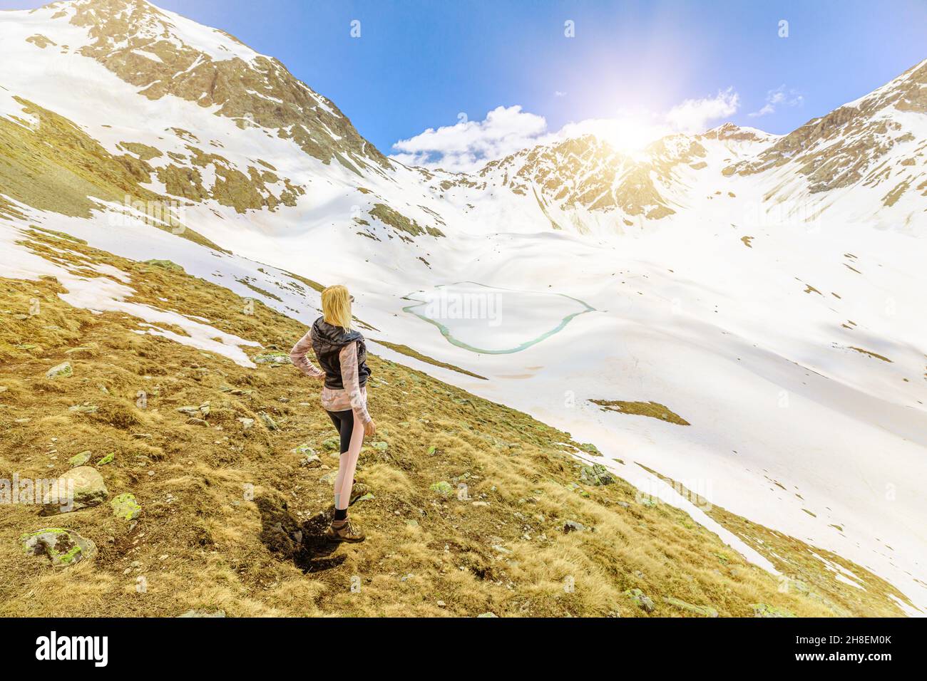 Swiss woman by the iced lake called Lej Muraglat of the end of mountain excursion in the snow trail on top of Muottas Muragl mount. Switzerland Stock Photo