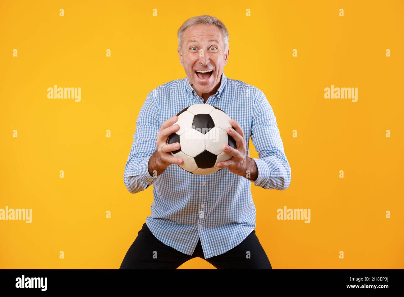 Mature man posing with soccer ball on yellow background Stock Photo - Alamy