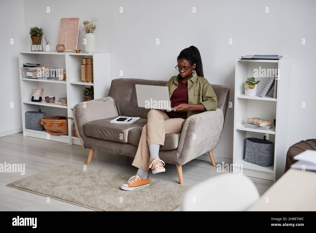 Full length portrait of young African-American woman working from home in comfortable setting, copy space Stock Photo