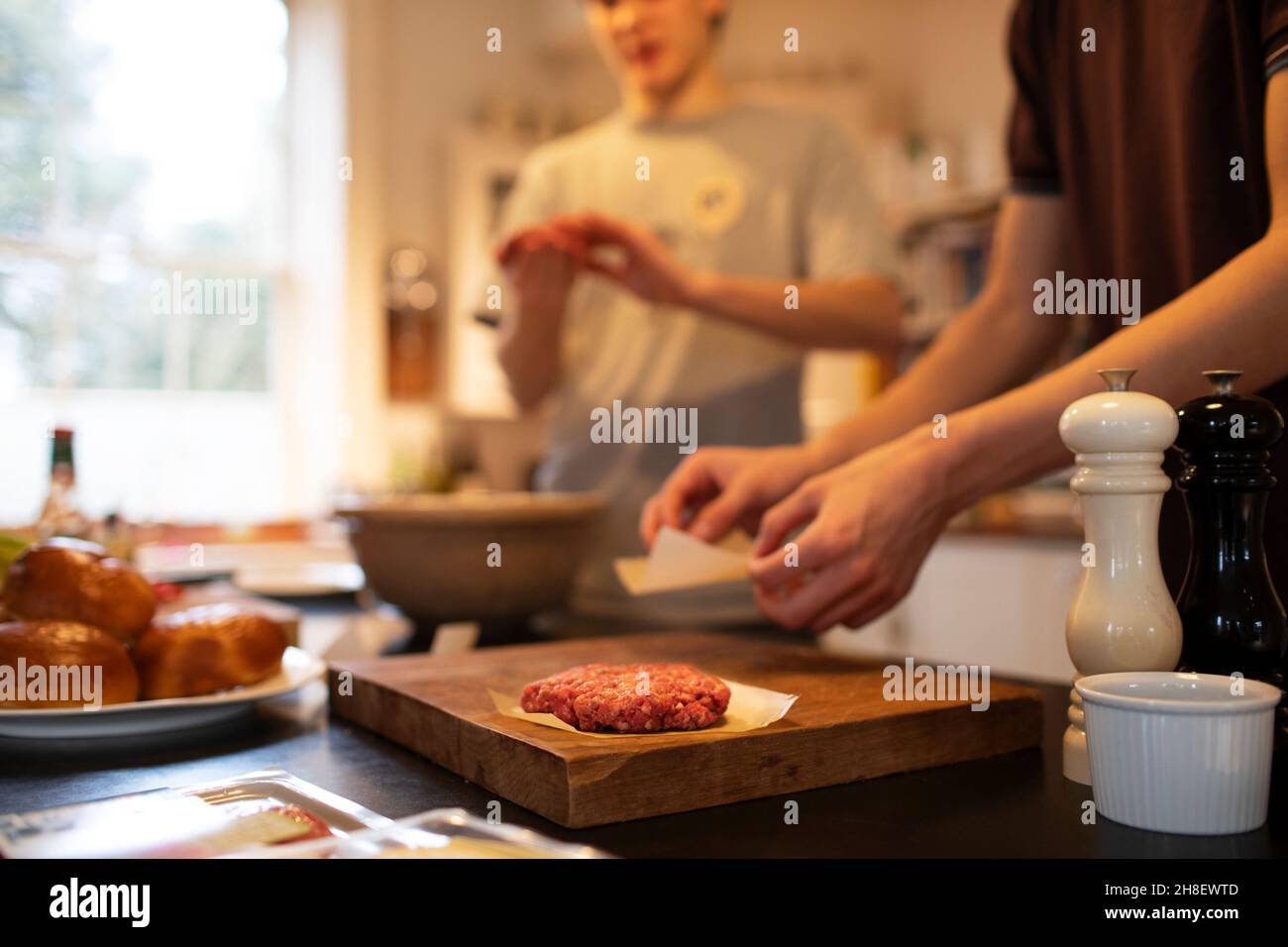 Teenage boys making hamburger patties in kitchen Stock Photo