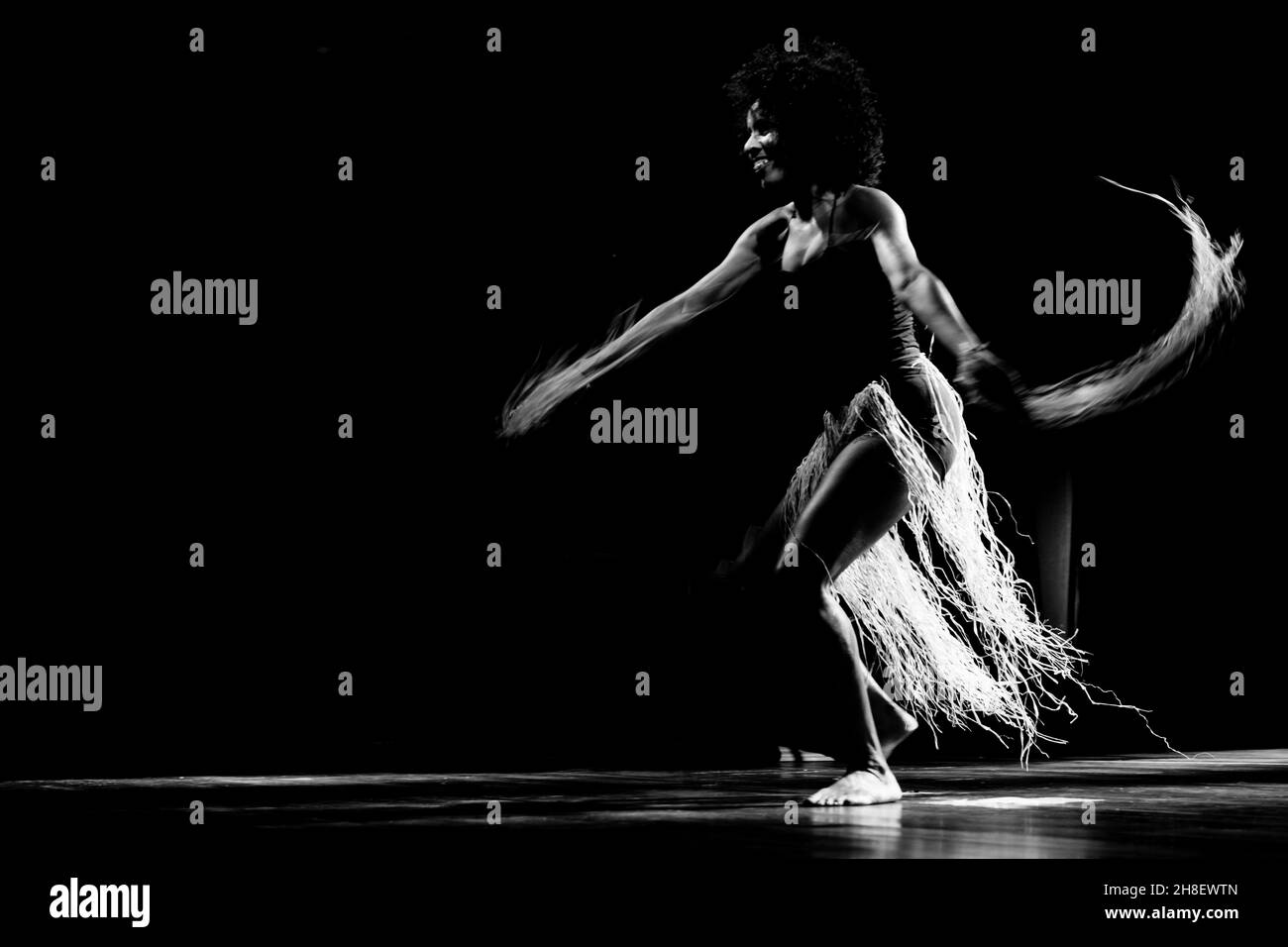 Black-and-white portrait of a woman dancing on stage against black background. Salvador, Bahia, Brazil. Stock Photo