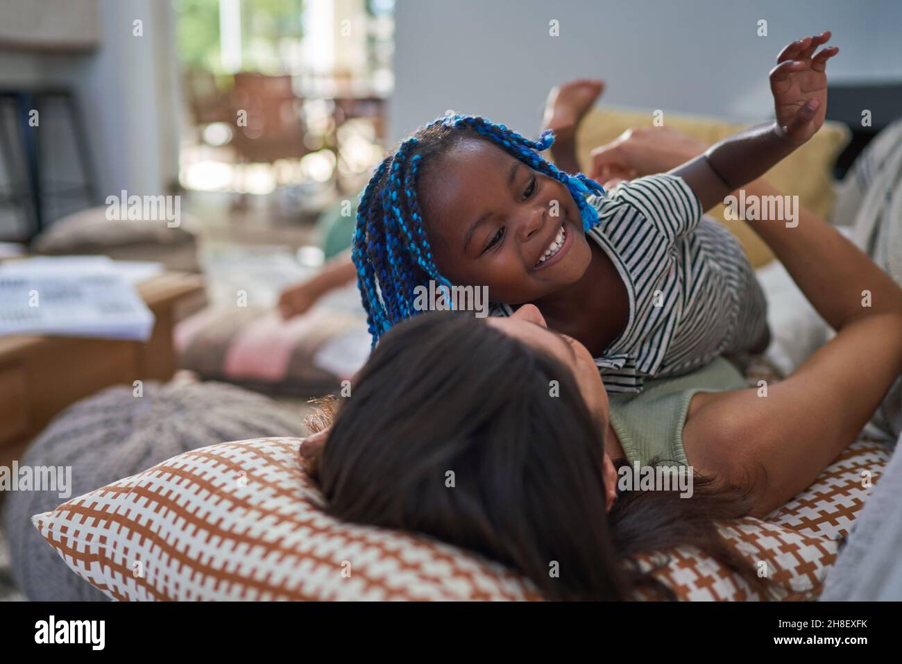 Happy playful mother and daughter on living room sofa Stock Photo