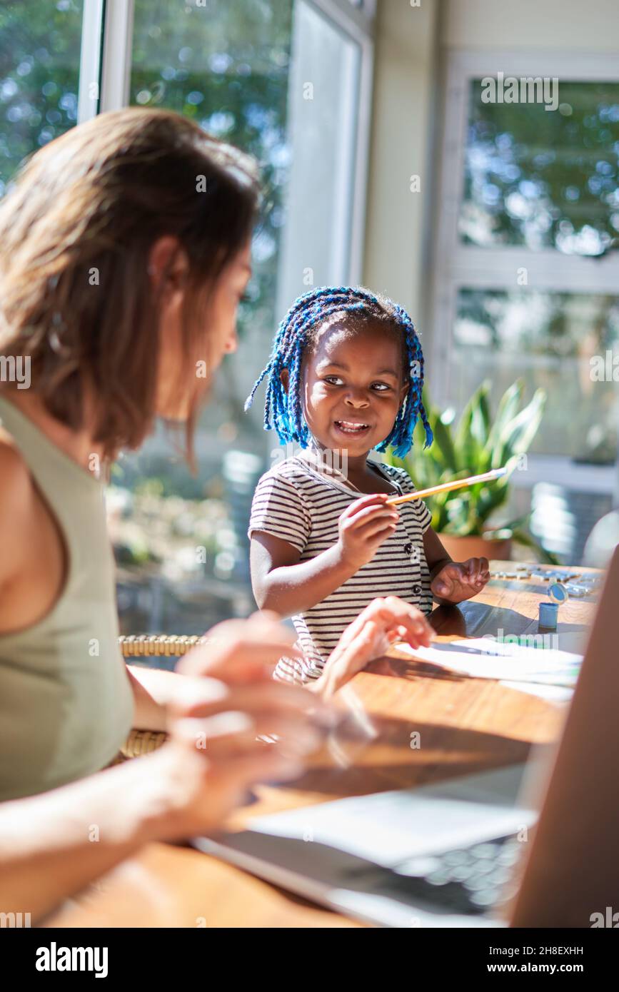 Cute toddler girl painting at sunny table with mother Stock Photo