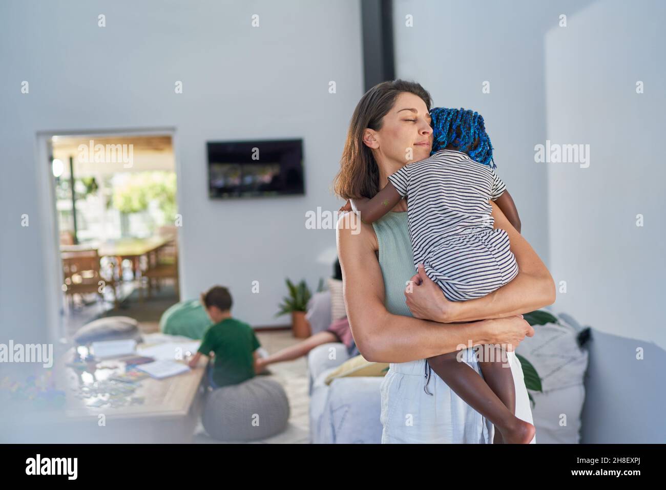 Serene mother holding toddler daughter at home Stock Photo