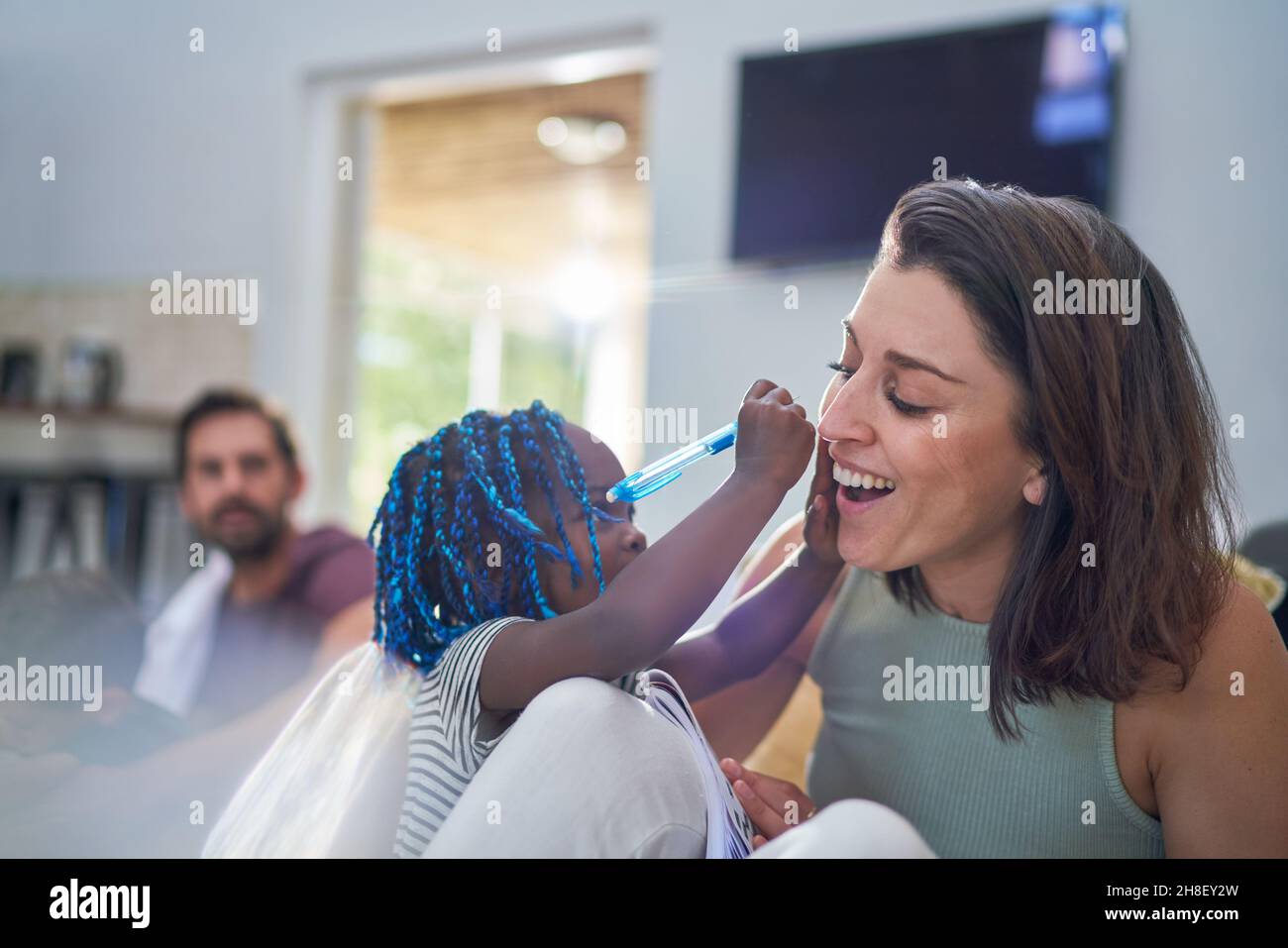 Playful toddler girl with pen writing on mother Stock Photo