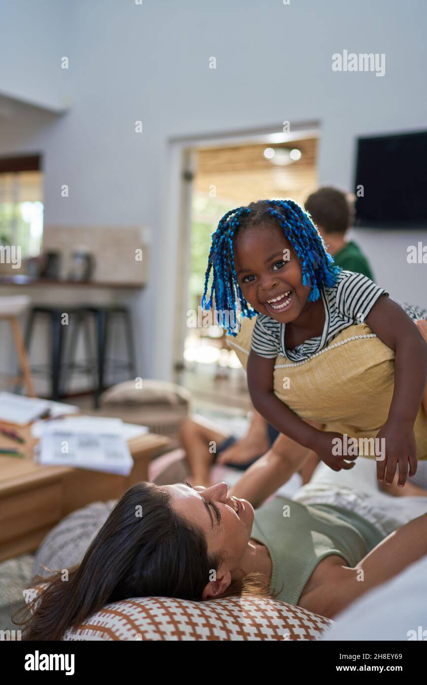 Portrait happy toddler daughter playing with mother on sofa Stock Photo