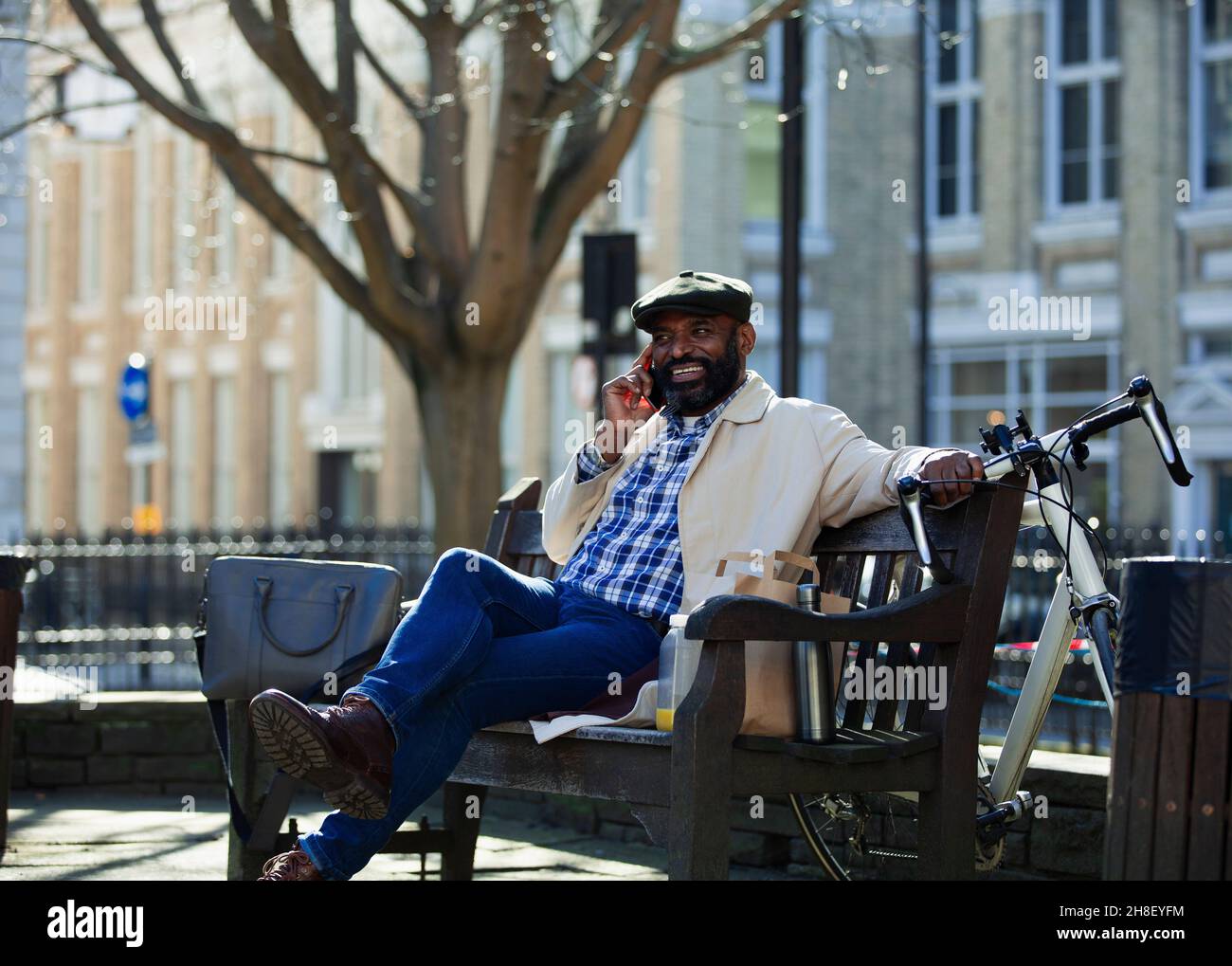 Businessman talking on smart phone on bench in city park Stock Photo