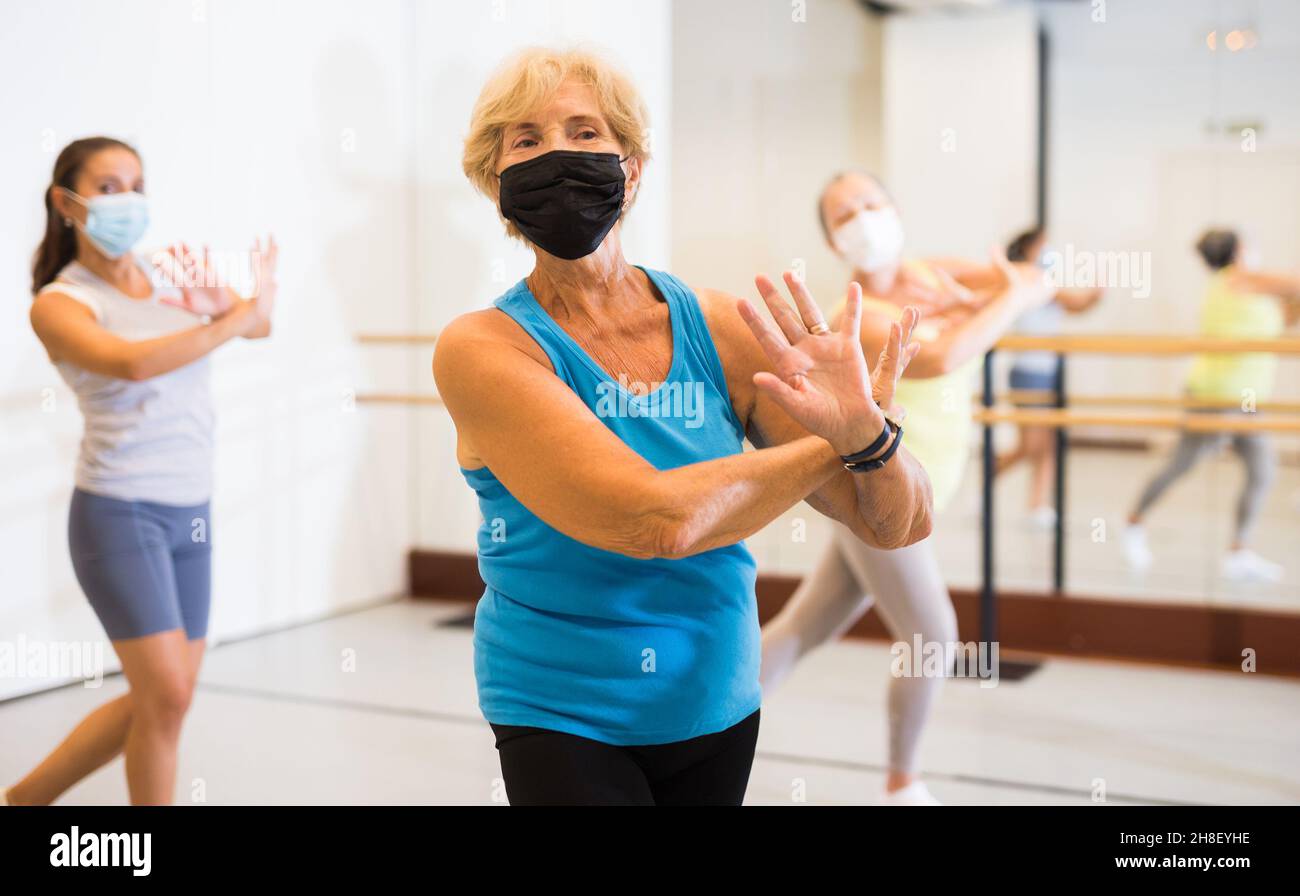 Old lady in mask dancing with group in studio Stock Photo