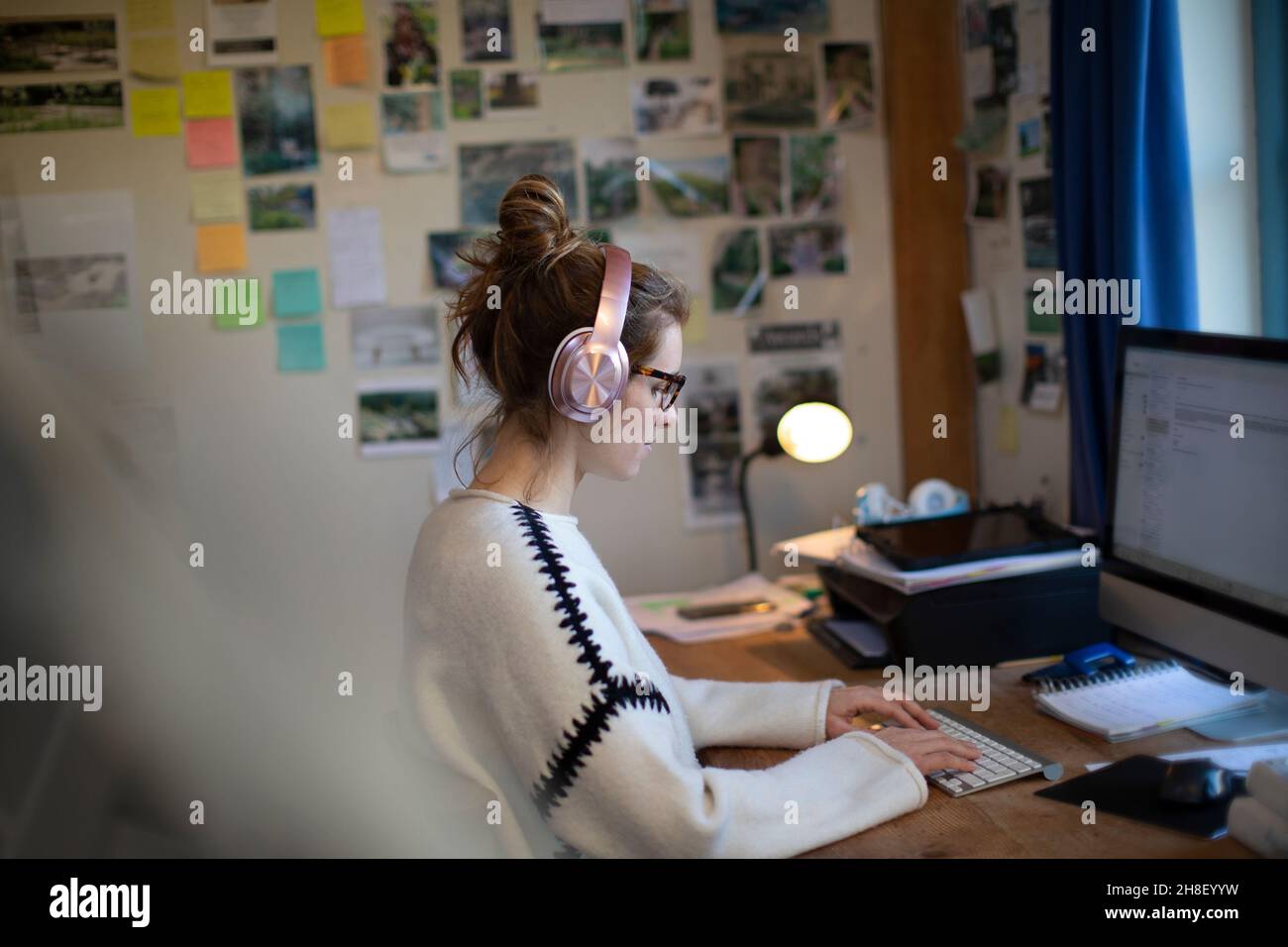 Woman with headphones working from home at computer in home office Stock Photo