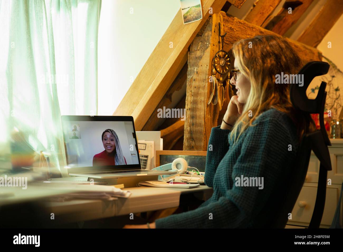 Woman video chatting with colleague on laptop screen in home office Stock Photo