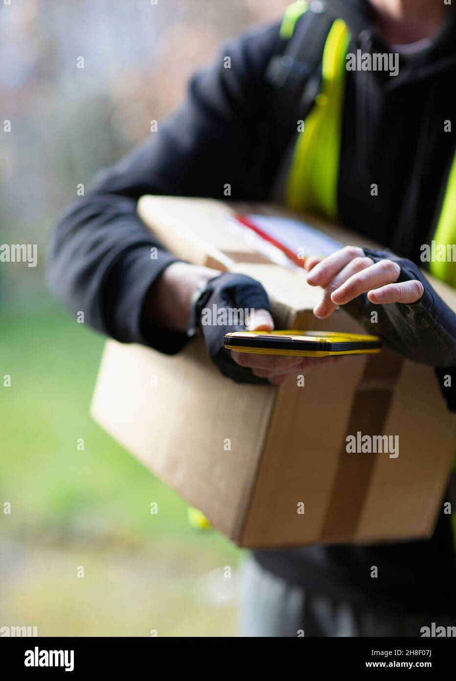Courier with smart phone delivering package Stock Photo