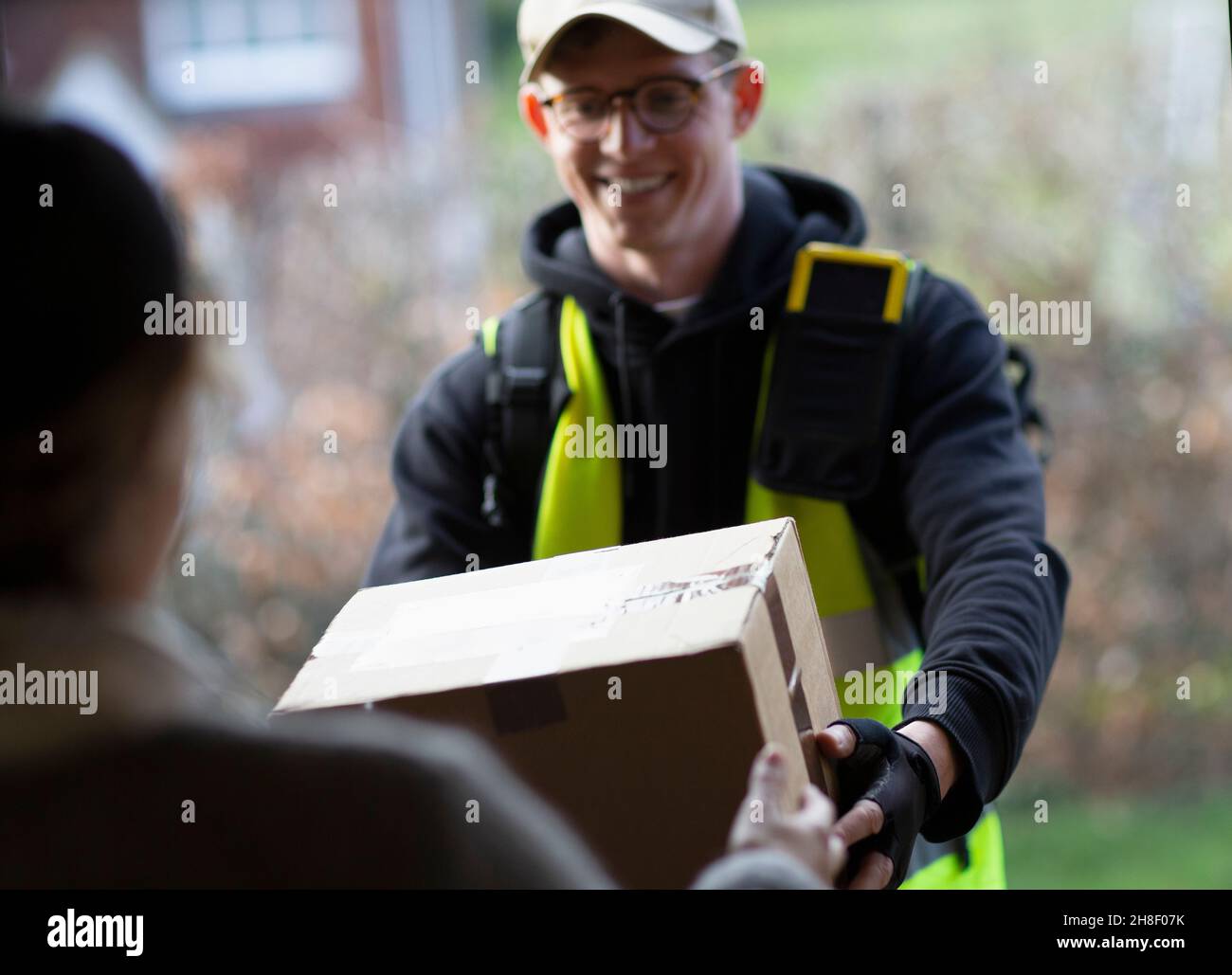 Friendly male courier delivering package at front door Stock Photo