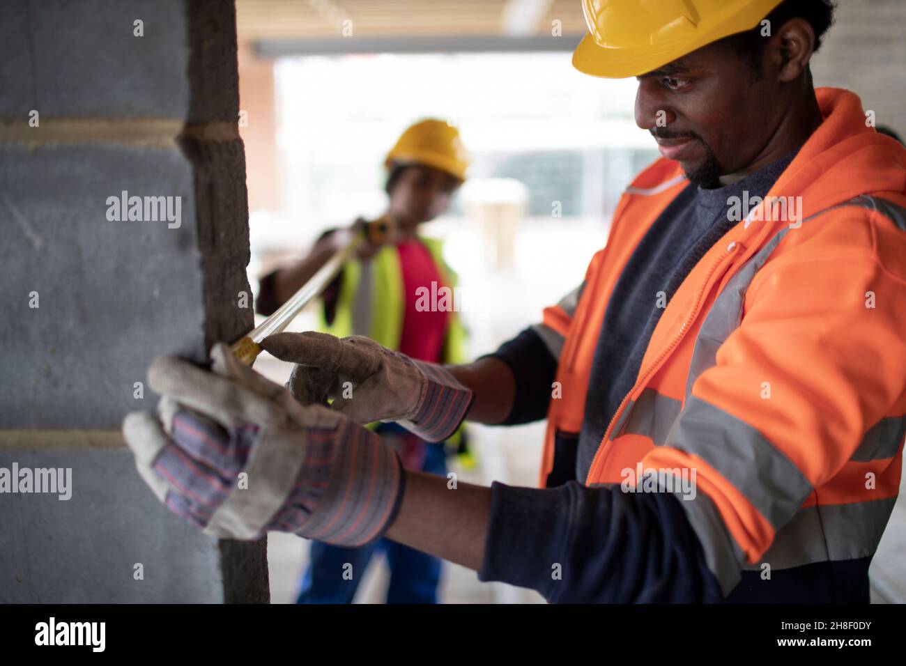 Construction workers using tape measure at construction site Stock Photo