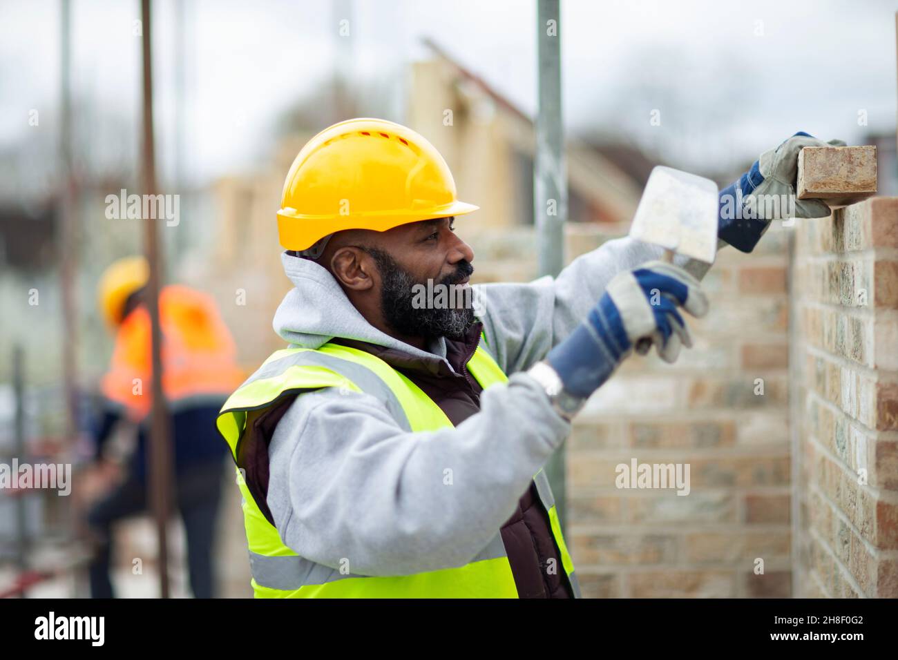 Male construction worker laying bricks at construction site Stock Photo
