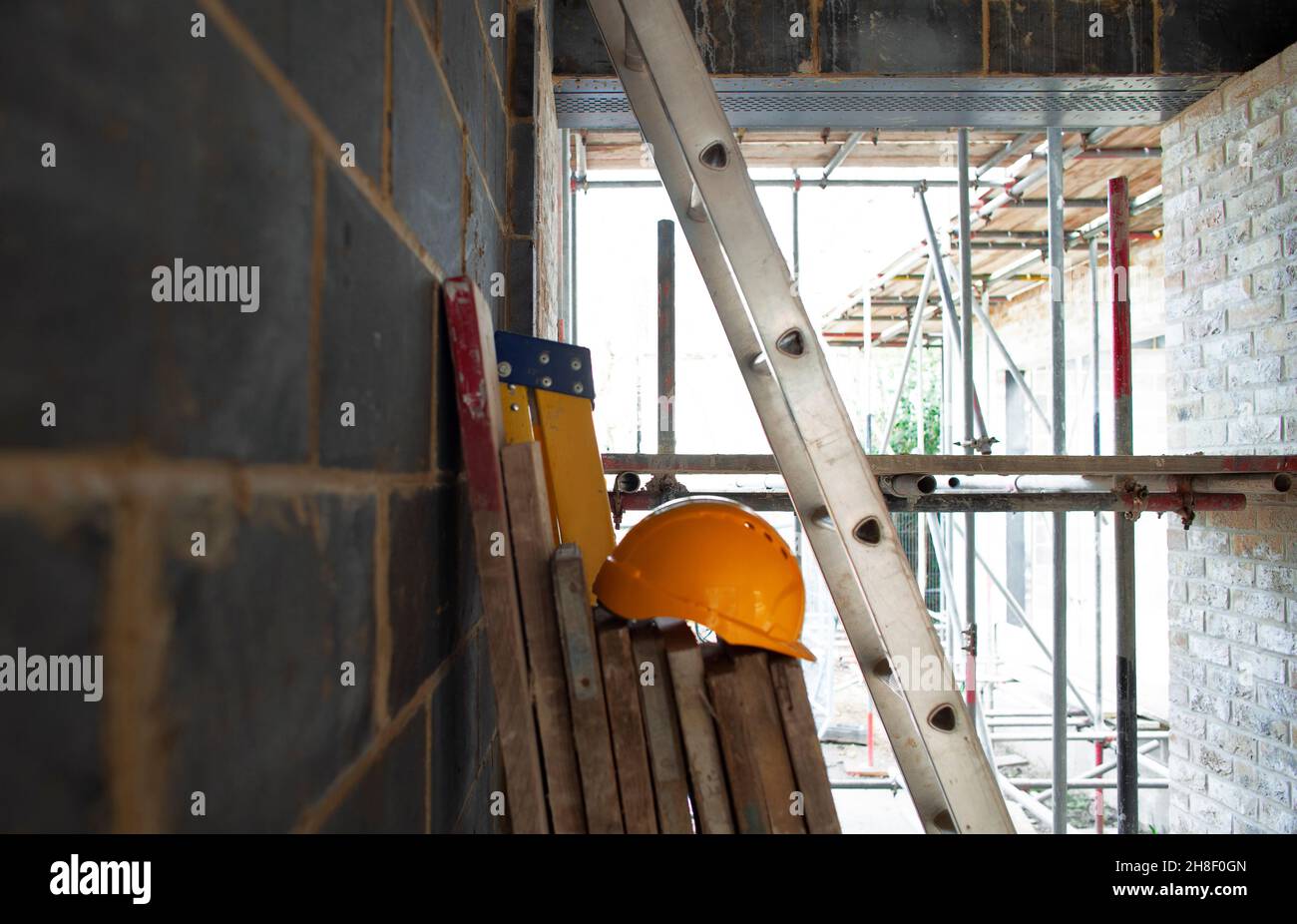 Hard hat, wood planks and ladders at construction site Stock Photo