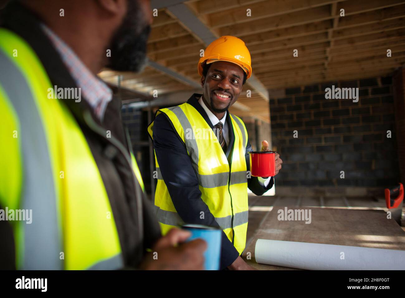 Male architects drinking coffee at construction site Stock Photo