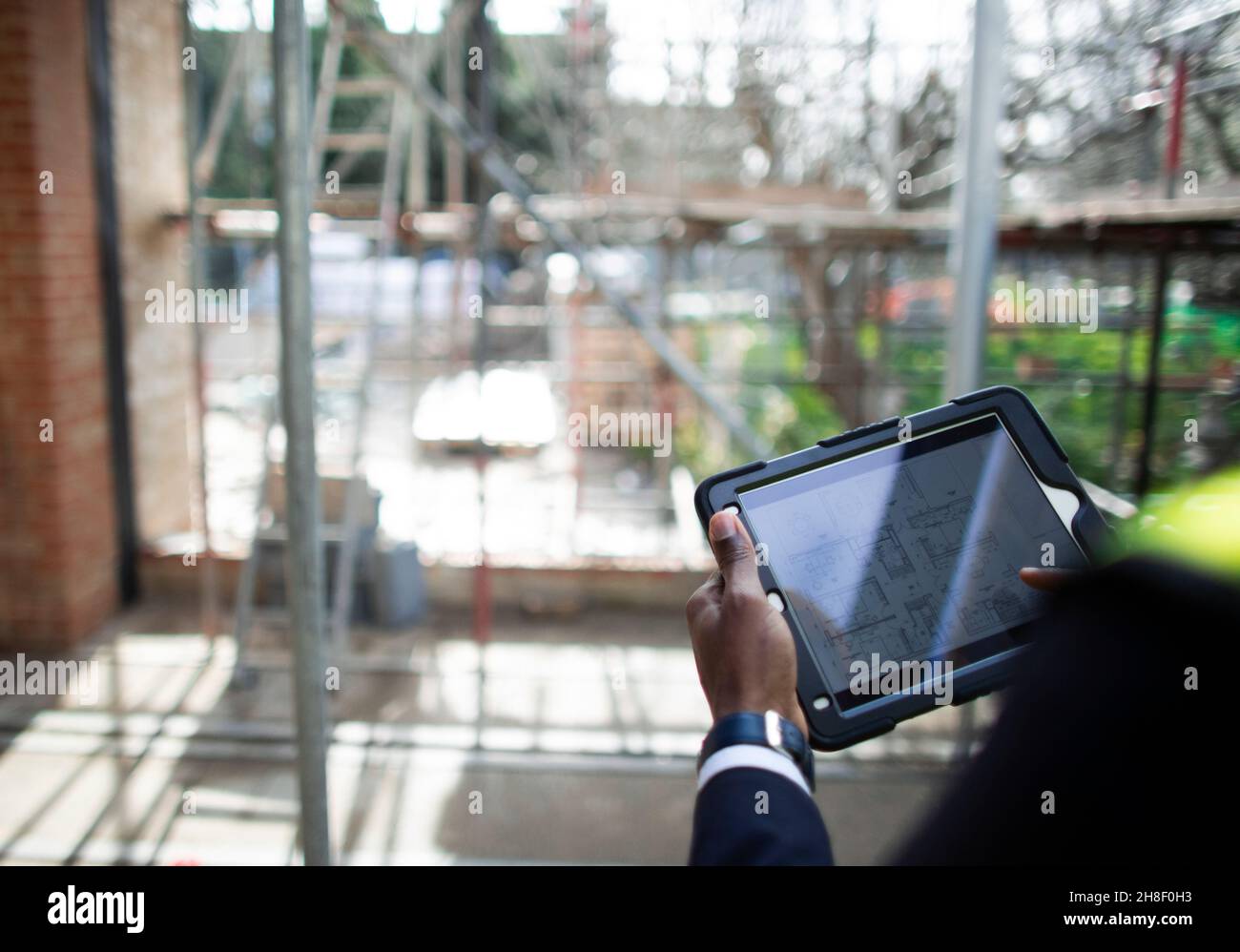 Engineer looking at blueprints on digital tablet at construction site Stock Photo