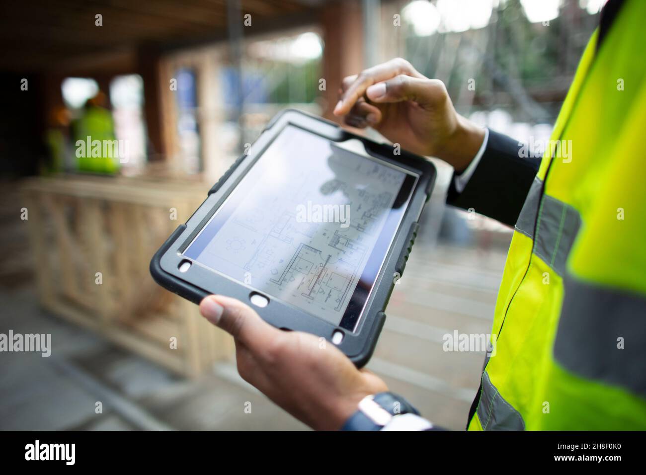 Male architect looking at blueprints on digital tablet Stock Photo