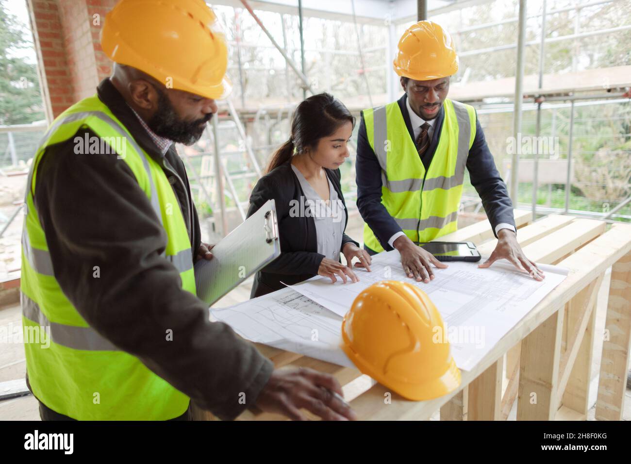 Architects and engineer looking at blueprints at construction site Stock Photo