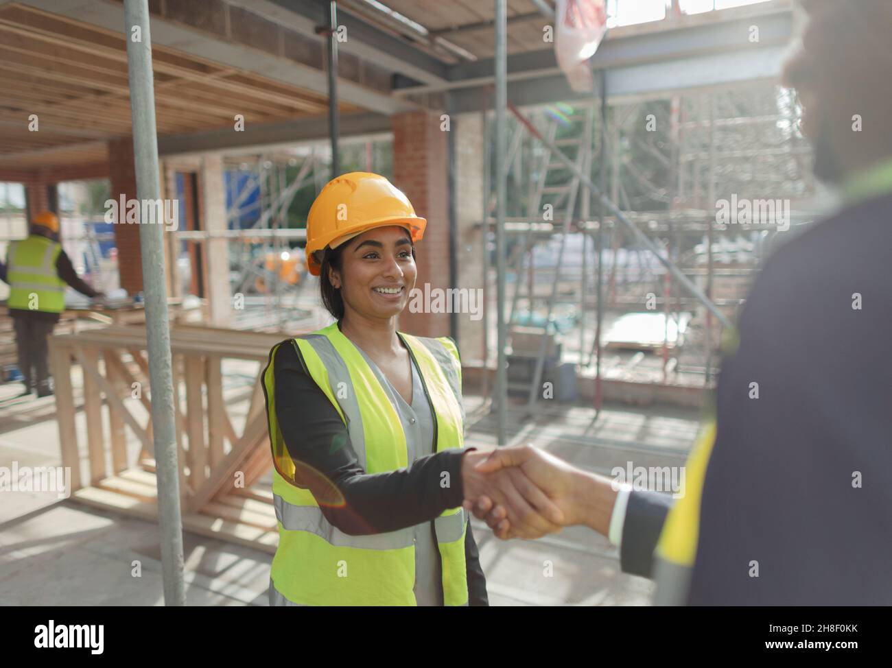 Architect and forewoman shaking hands at construction site Stock Photo