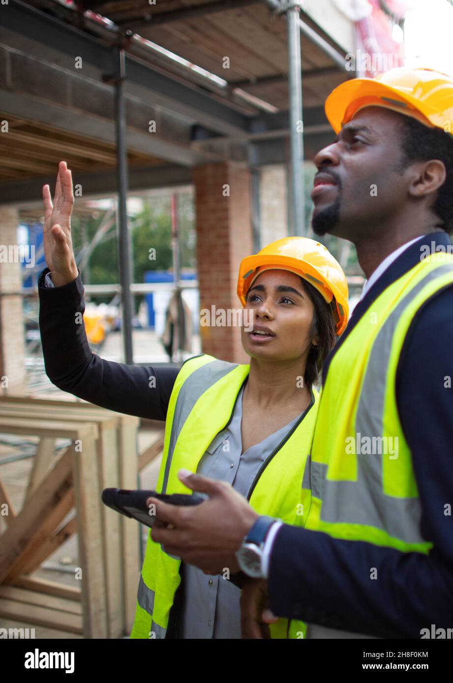 Engineers with digital tablet talking at construction site Stock Photo