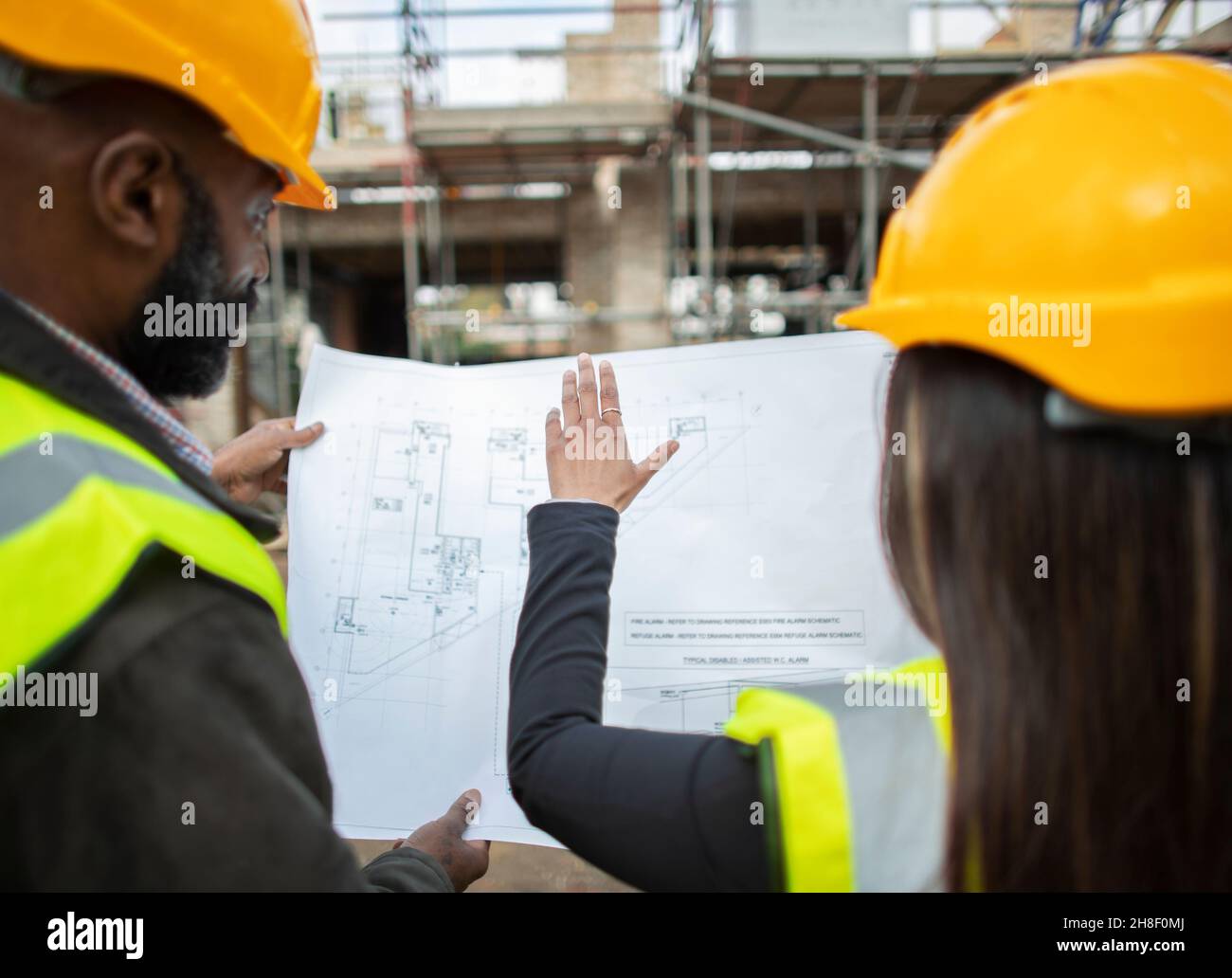 Architects with blueprints at construction site Stock Photo