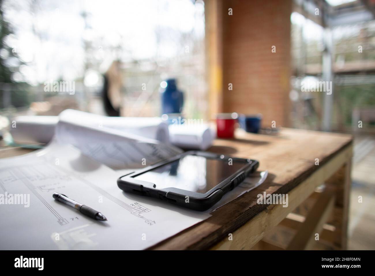 Digital tablet and blueprints at construction site Stock Photo