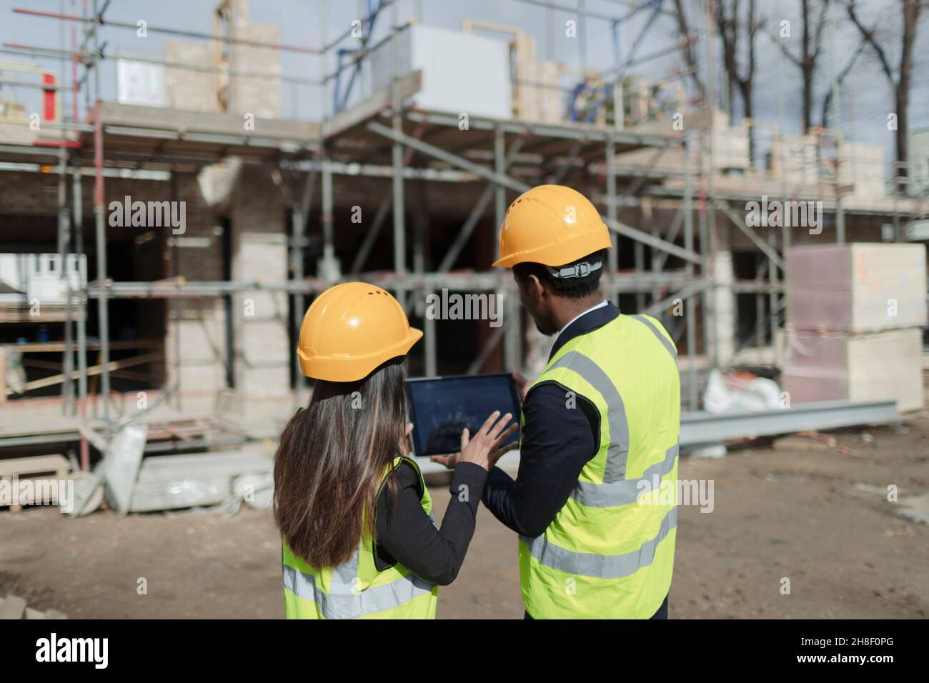 Engineers with digital tablet at sunny construction site Stock Photo