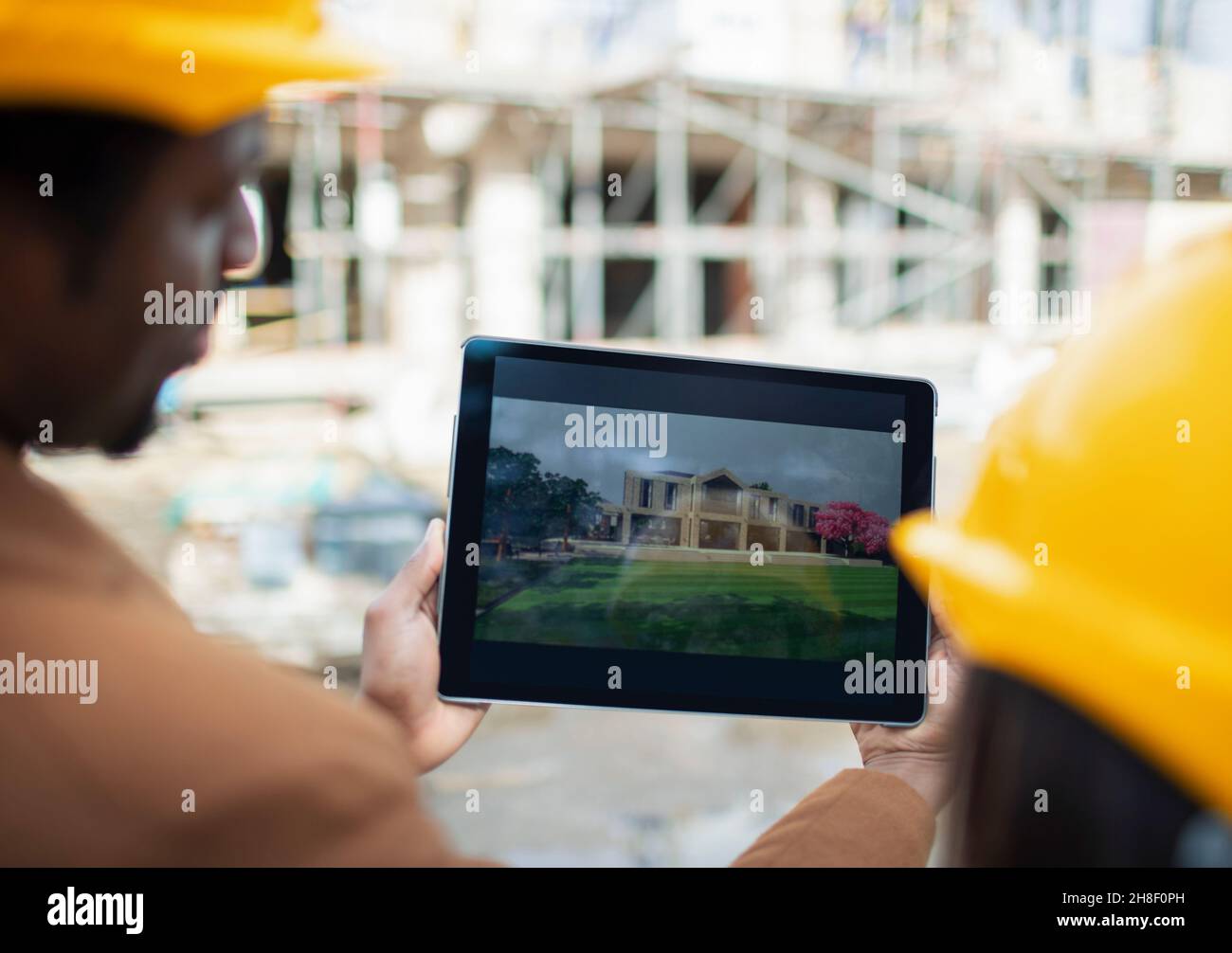 Engineers looking at digital rendering on tablet at construction site Stock Photo