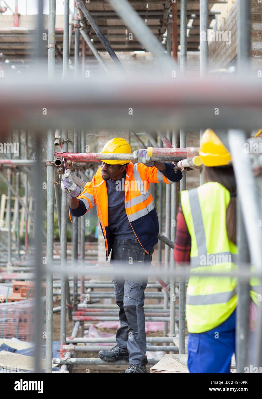 Construction workers assembling scaffolding at construction site Stock Photo