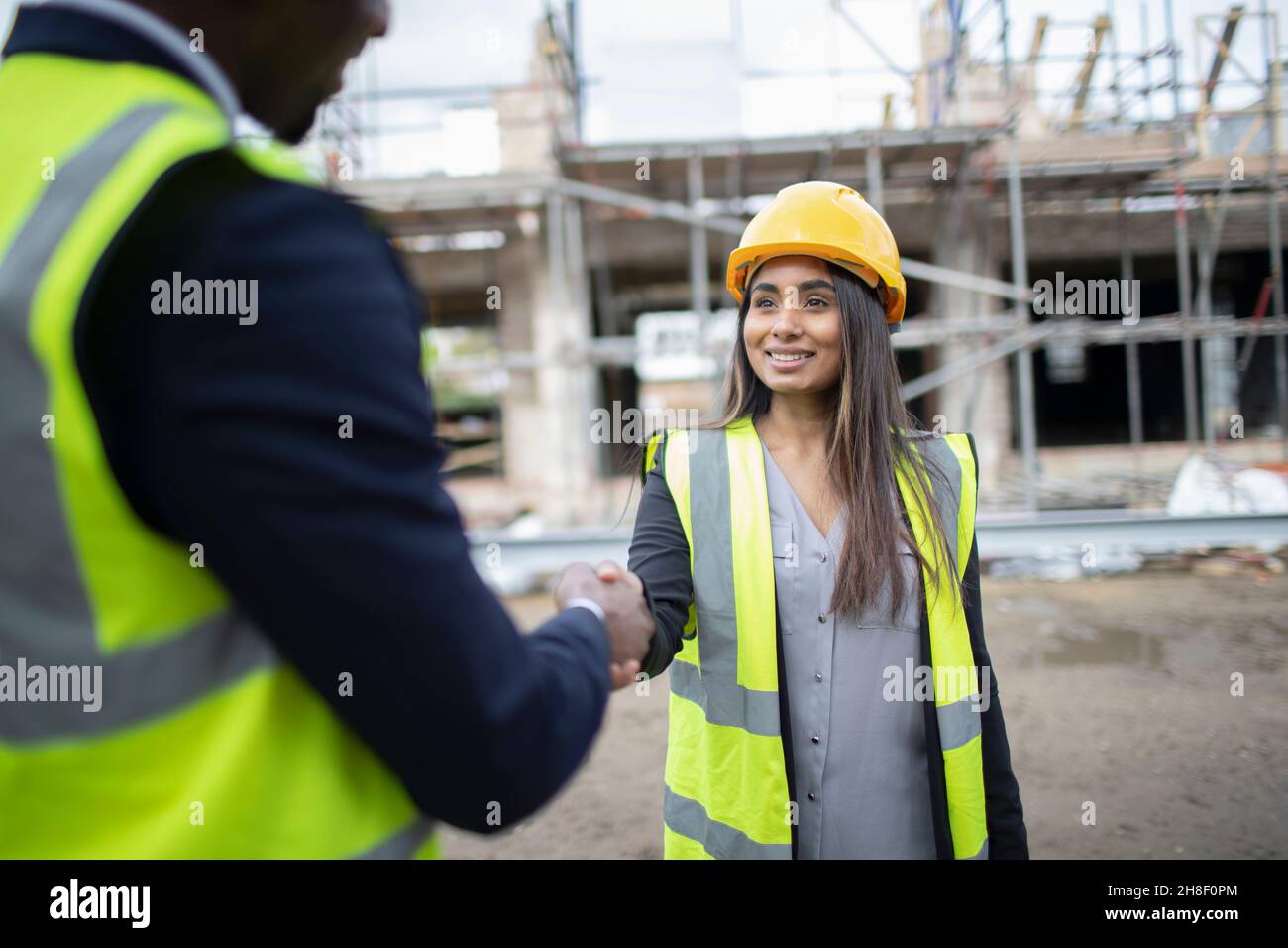 Engineer and forewoman shaking hands at construction site Stock Photo