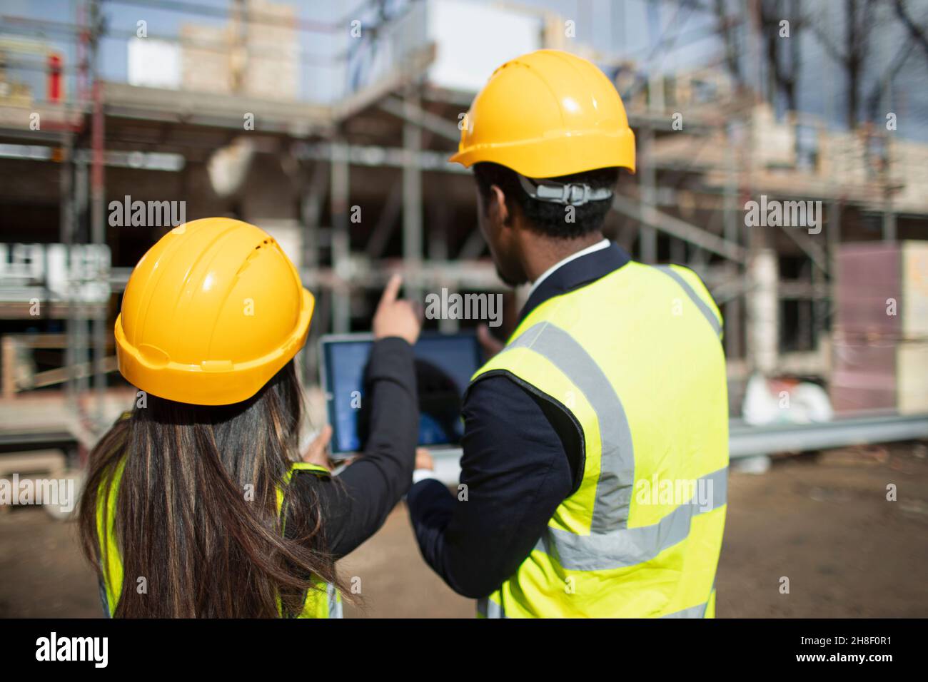 Engineer and architect with digital tablet at sunny construction site Stock Photo