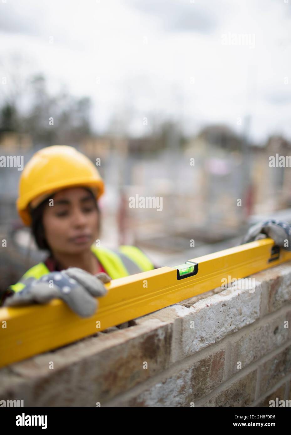 Female construction worker using level tool on brick wall Stock Photo