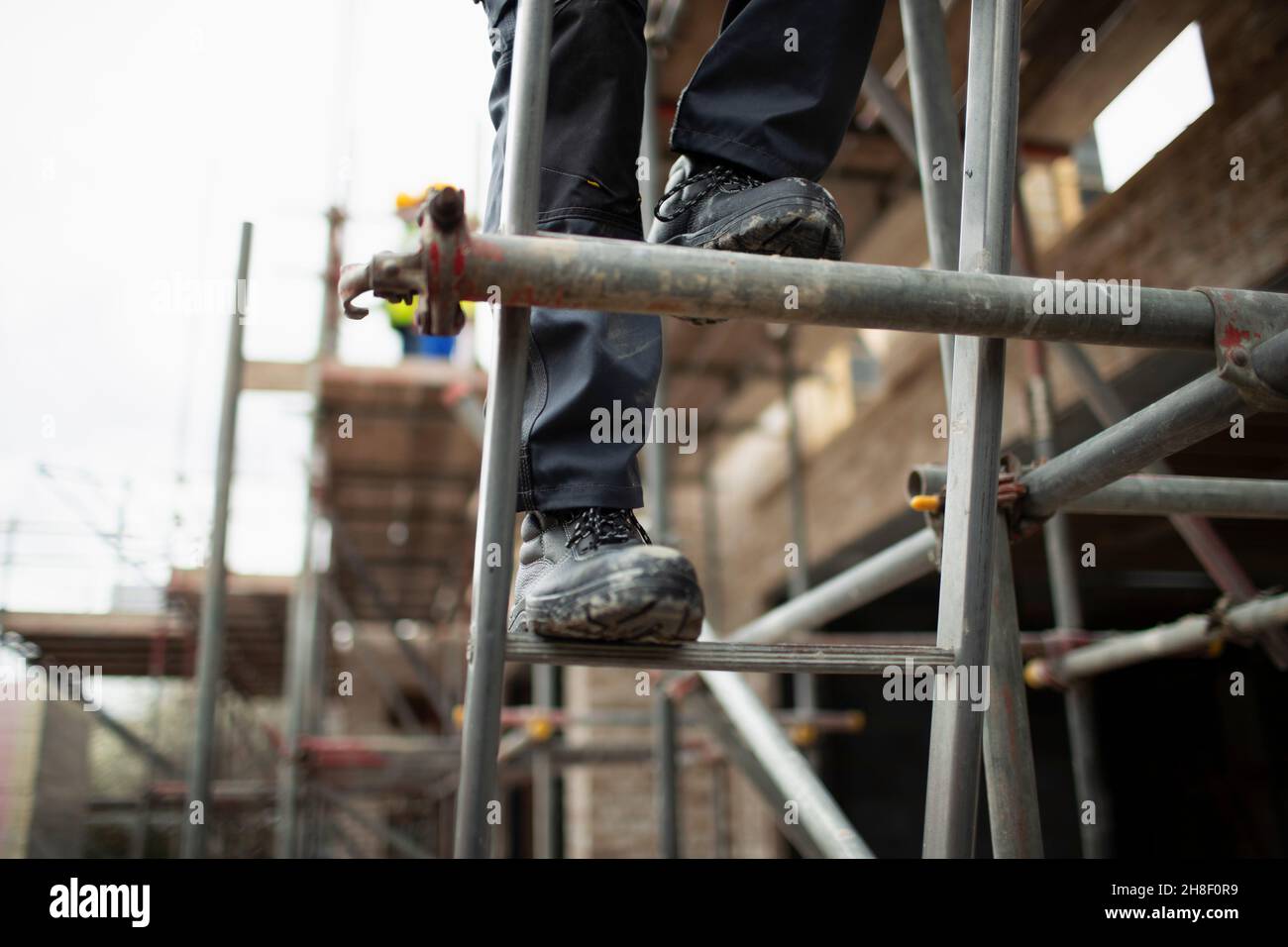 Construction worker climbing scaffolding at construction site Stock Photo