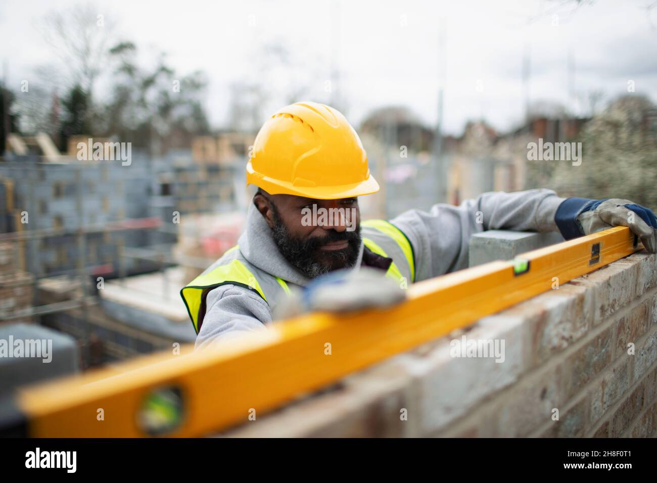 Male construction worker using level tool on brick wall Stock Photo