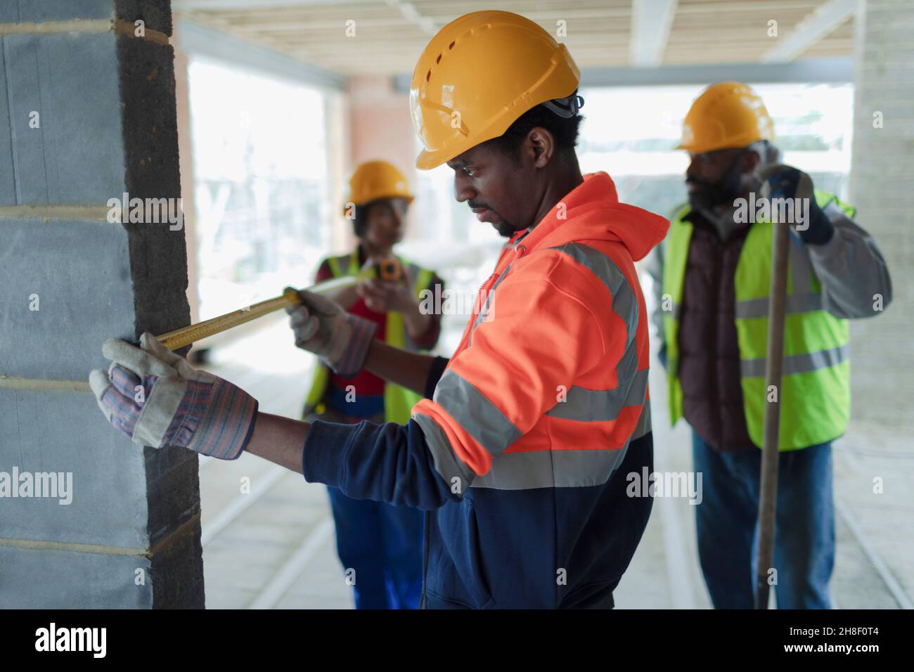 Construction workers with tape measure at construction site Stock Photo