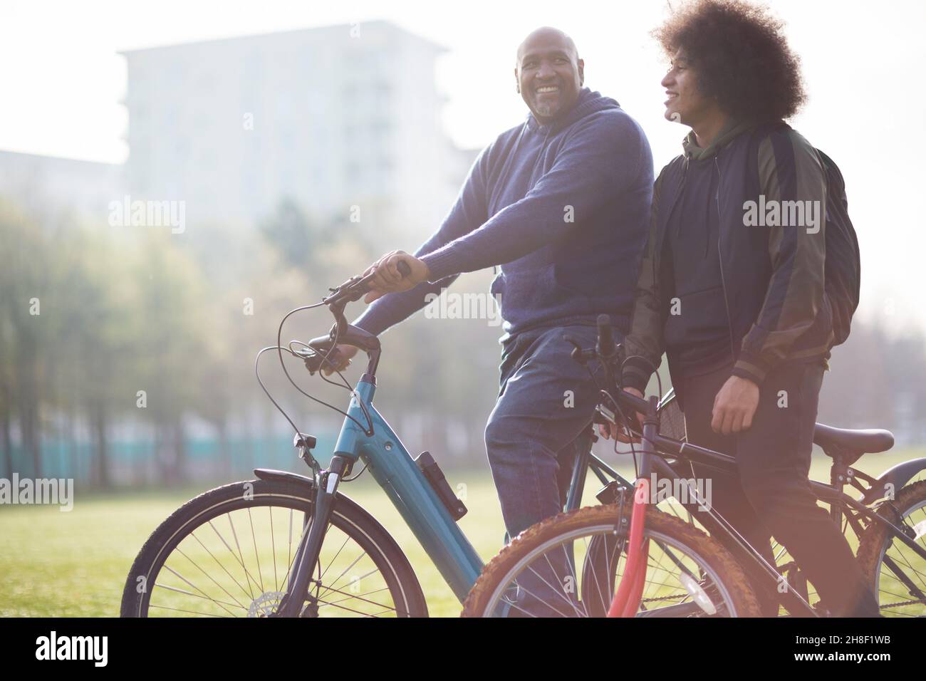 Happy father and son with bicycles in urban park Stock Photo