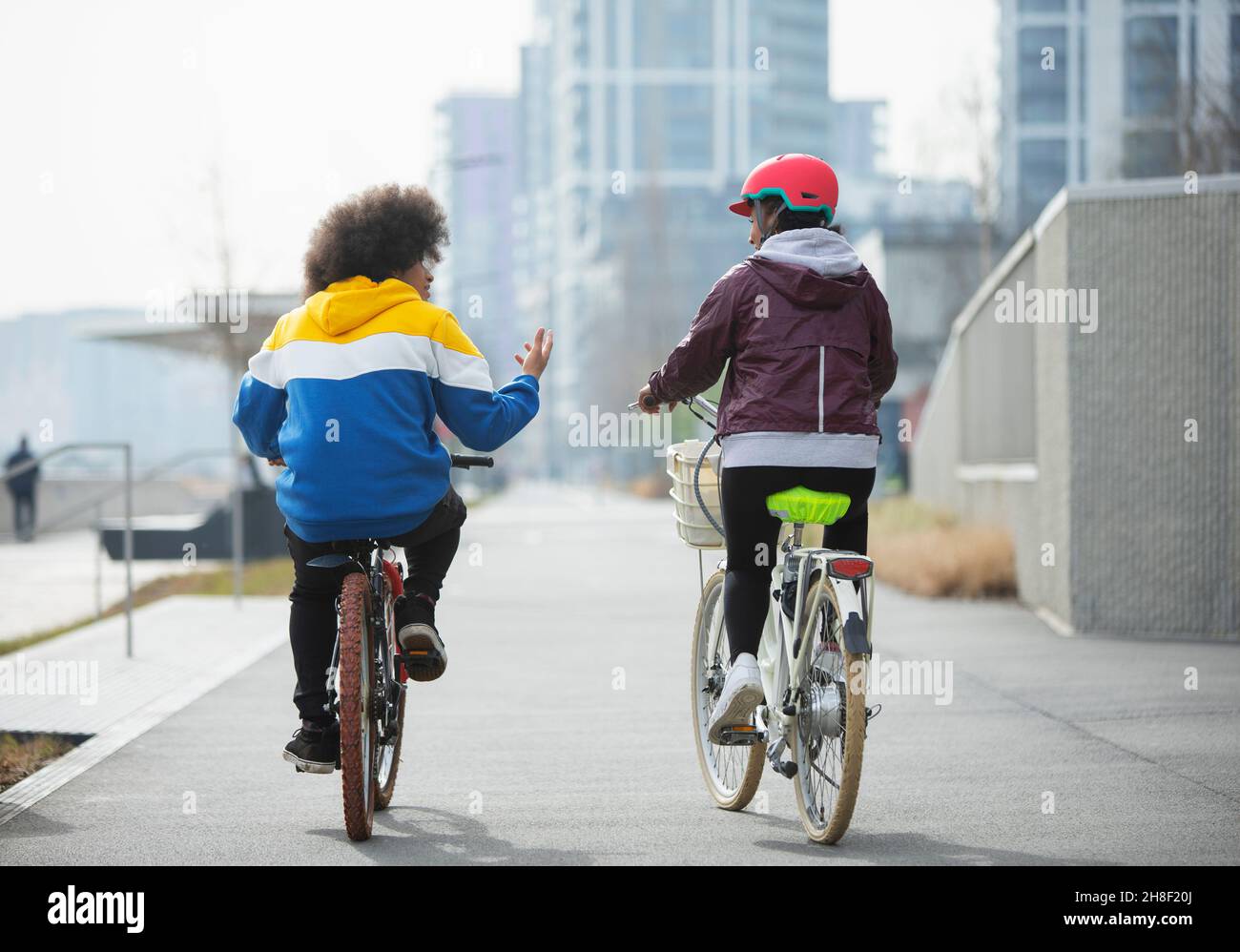 Teen friends riding bicycles on bike path in city Stock Photo