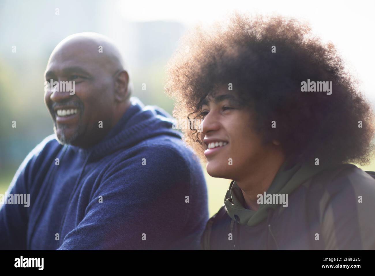 Happy father and teen son looking away Stock Photo