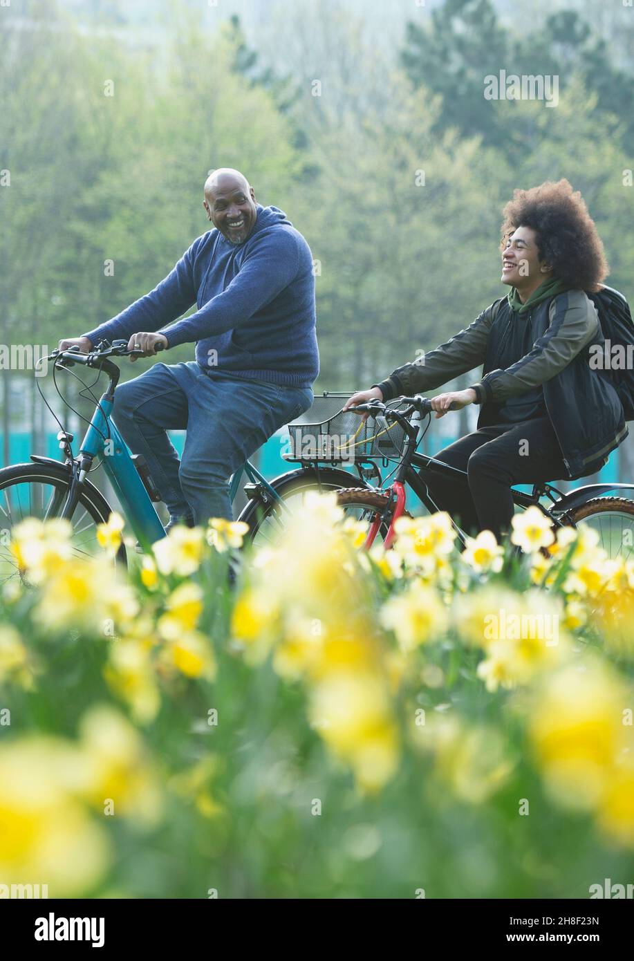 Happy father and teen son riding bicycle in spring park Stock Photo