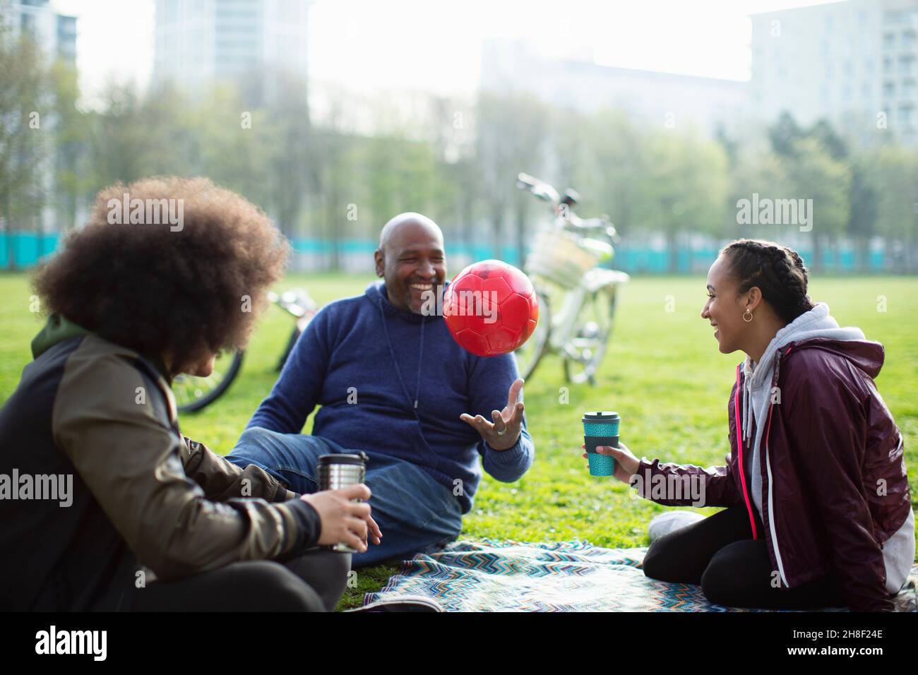Family with soccer ball and coffee in park grass Stock Photo